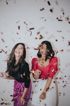 two women standing next to each other in front of confetti