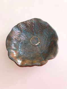 a ring sits on top of a leaf shaped bowl