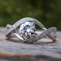 This 14K white gold solitaire engagement ring features a swirl shaped band and a 6 mm Moissanite by Charles & Colvard. The band is accented with smaller moissanite stones making this unique engagement ring have a 1.02ctw.What Is A Moissanite? Moissanite is a rare, naturally occurring mineral also known as silicon carbide. It was first discovered by a chemist, Dr. Henri Moissan, at the site of a massive meteorite strike in Arizona. It was deemed moissanite in his honor. Charles & Colvard' White Gold Solitaire Engagement Ring, Bubble Ring, Moissanite Solitaire Ring, White Gold Solitaire, Spiral Ring, Band Jewelry, Band Engagement Ring, Wedding Rings Vintage, Solitaire Ring