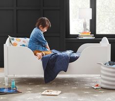 a little boy sitting on top of a white bed