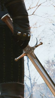 a person holding two swords in their hands with trees in the back ground behind them