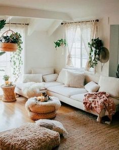 a living room filled with lots of white furniture and plants on the windows sill