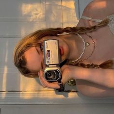 a woman holding up a camera in front of her face and wearing a bra top