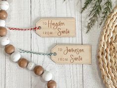 two wooden tags with names on them sitting next to a wicker basket and pine branches