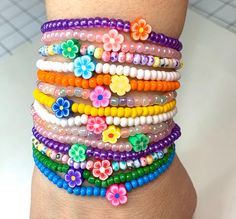 a woman's arm with colorful bracelets and flowers on the wrist, all made out of plastic beads