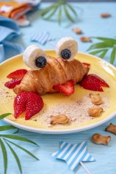 a croissant with strawberries and bananas on it is sitting on a plate