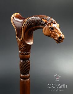 a carved wooden horse head on top of a wooden pole with an intricate carving pattern