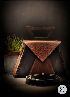 a brown leather bag sitting on top of a table next to a potted plant