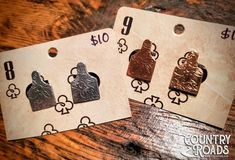 three price tags with different designs on them sitting on a wooden table next to each other