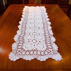 a table runner with white crocheted doily sitting on top of a wooden table