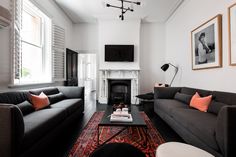 a living room with two couches and a television on the wall in front of a fireplace