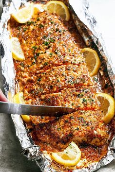 someone is cutting up some food on tin foil with lemons and parmesan cheese