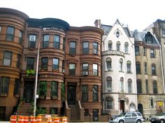 a row of brownstone townhouses with cars parked on the street