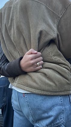 a person with their back to the camera and his hand on his hip, wearing a ring