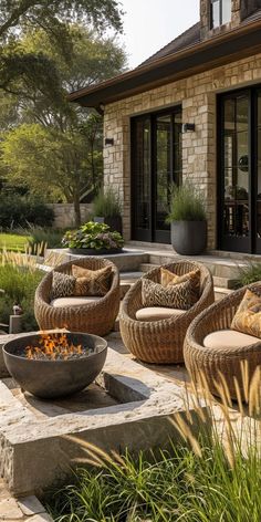 an outdoor fire pit surrounded by chairs and plants