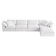 a white sectional couch with pillows on it's back and side facing the sofa