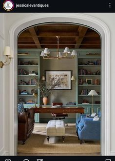 a living room filled with furniture and bookshelves next to a doorway that leads into a sitting area