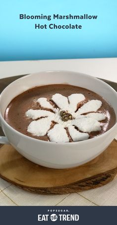 there is a bowl of hot chocolate with marshmallows in it on the plate