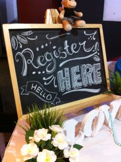 a teddy bear sitting on top of a table next to a sign that says register here