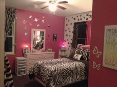 a bedroom decorated in pink and black with zebra print bedding, dressers, mirror and lights