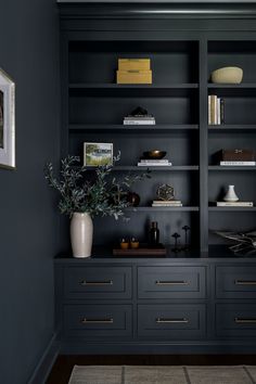 a black bookcase with two vases and books on it in a living room