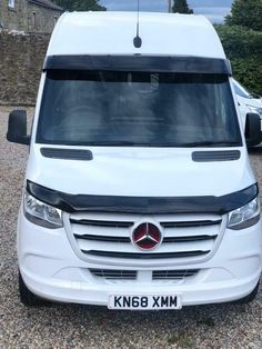 the front end of a white van parked in gravel