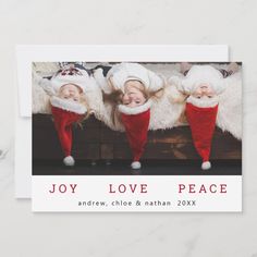 three children wearing christmas hats and red pants, with the words joy love peace above them