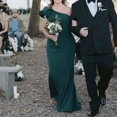 a man in a tuxedo walking next to a woman in a green dress