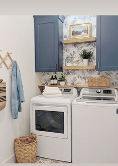 a washer and dryer in a small laundry room with blue cupboards on the wall