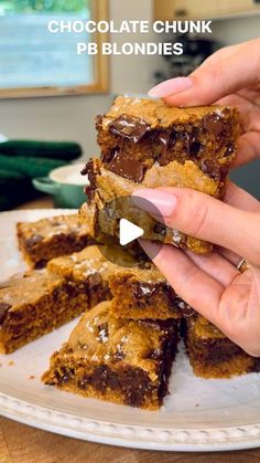 chocolate chunk pb blondies are stacked on a plate and being cut into squares