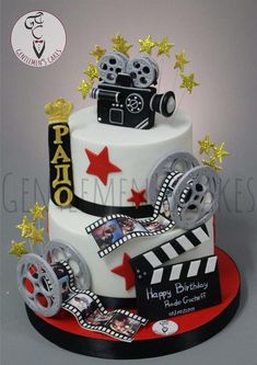 a birthday cake decorated with film reels and stars on the top is an image of a movie camera