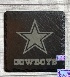 a black slate coaster with the word cowboys on it and a star in the center