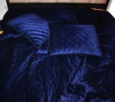 an unmade bed with blue comforter and pillows on it's bottom half