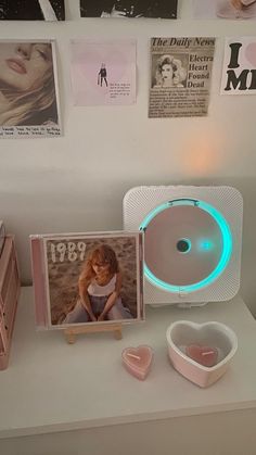 a white table topped with pictures and heart shaped bowls next to a wall mounted fan