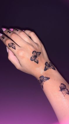 a woman's hand with butterfly tattoos on it