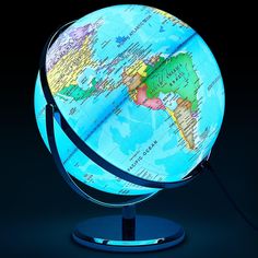 an illuminated globe on a black background with the light turned on and plugged in