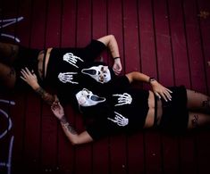 two women in skeleton shirts laying on the ground