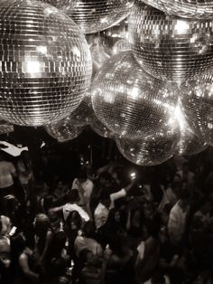 many shiny disco balls are hanging from the ceiling in front of a large group of people