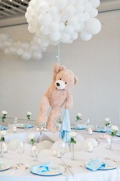 a teddy bear hanging from the ceiling above a table with blue and white tables cloths