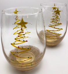 two wine glasses decorated with gold stars and confetti on the bottom one is filled with sand