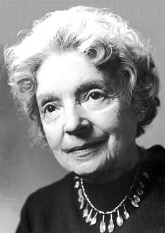 an old black and white photo of a woman with curly hair, wearing a necklace