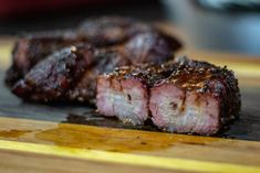 two pieces of meat sitting on top of a wooden cutting board