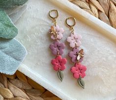 two pairs of pink and purple flowers are hanging from gold - plated earwires