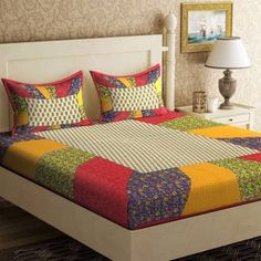 a bed with colorful bedspread and pillows in a room next to a lamp