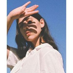 a woman is holding her hands up to the sun's shadow on her face