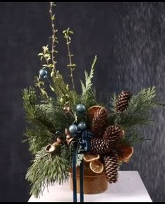 a vase filled with pine cones and greenery