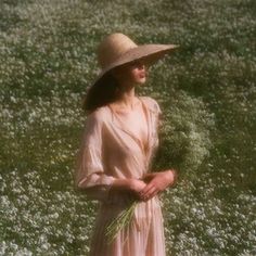 a woman in a dress and hat standing in a field