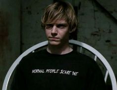 a young man is standing in front of a white chair with the words normal people scare me on it