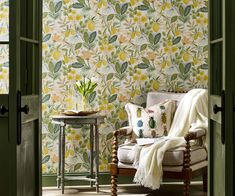 a chair and table in front of a floral wallpaper