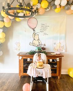 a winnie the pooh birthday party with balloons, cake and balloon garlands on the wall